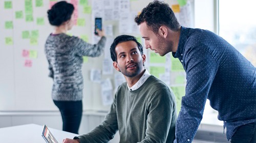 Two people helping each other behind the computer
