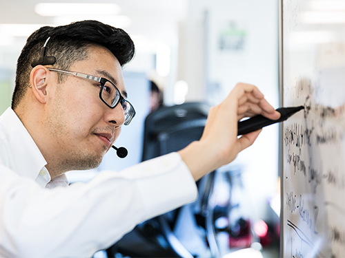 Man with a headset writing on a whiteboard