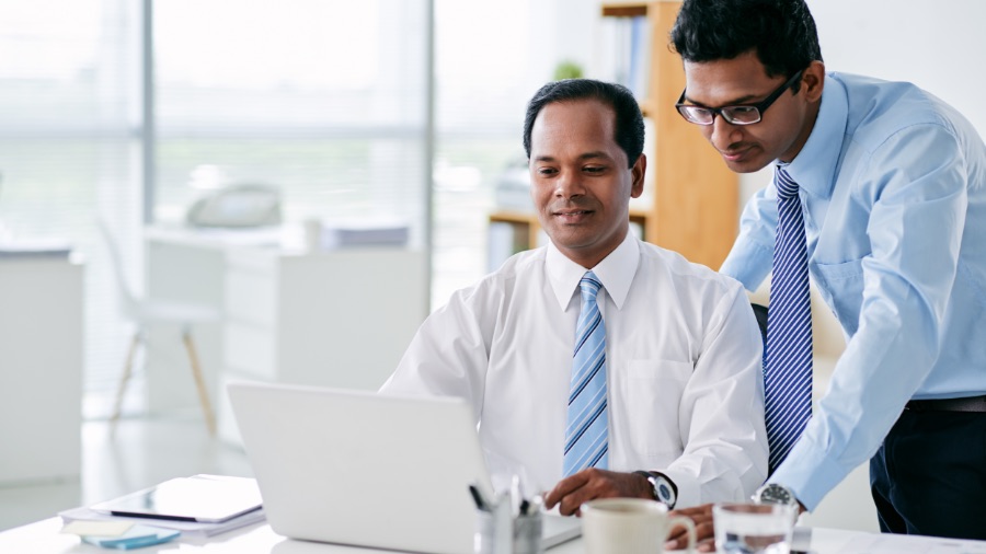 two men working on laptop in office