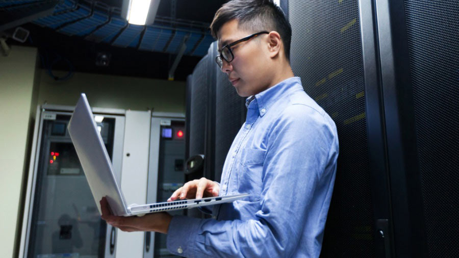 man working on laptop in server room