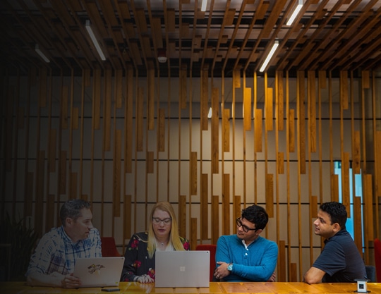 A group of tech workers hold meeting in common space of the office