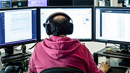 man working on three desktops