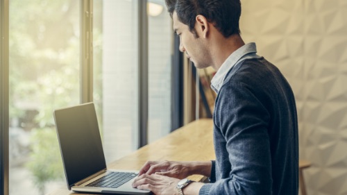 man standing and working on laptop