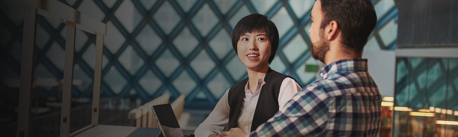 Woman and man sitting at a desk having a conversation in the Public Library with Surface Pro 4