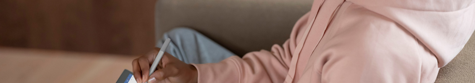 Adult female sitting on couch inside using Surface Pen to make notes