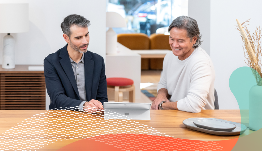 Two people sitting in a work environment with a tablet