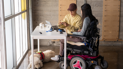 Woman in wheelchair installing the Microsoft Adaptive Accessories kit