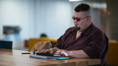 Man using braille keyboard while also working through a mobile phone