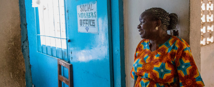 A smiling woman waiting at the door to a social worker's office