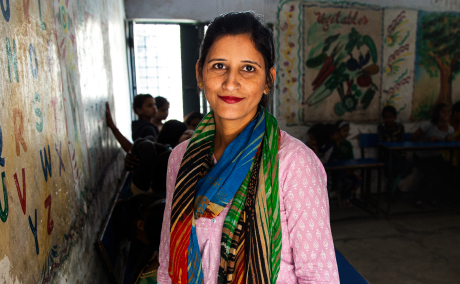 Brightly dressed woman smiles while children play at home