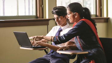 A teacher assists a student with online classwork