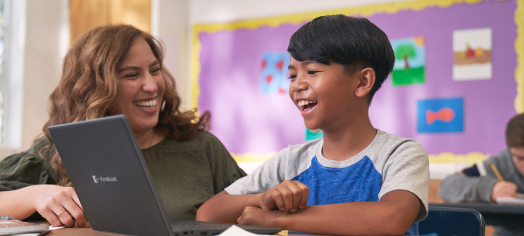 A smiling child and teacher with a laptop