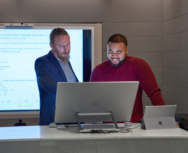Two men working on a Microsoft Surface Studio