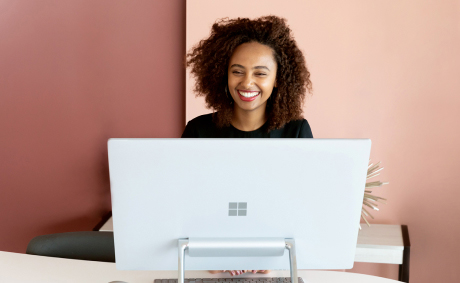 A smiling woman sits behind a Microsoft-branded computer