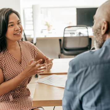 Two coworkers have a discussion in an office setting