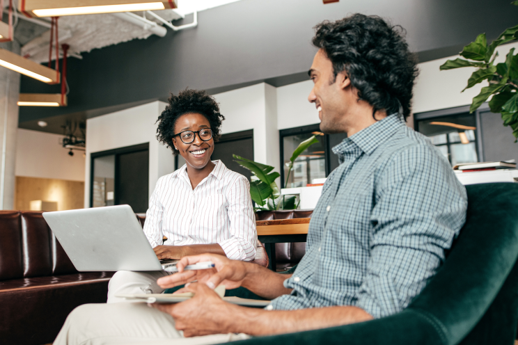 Two people smile and converse in an office setting