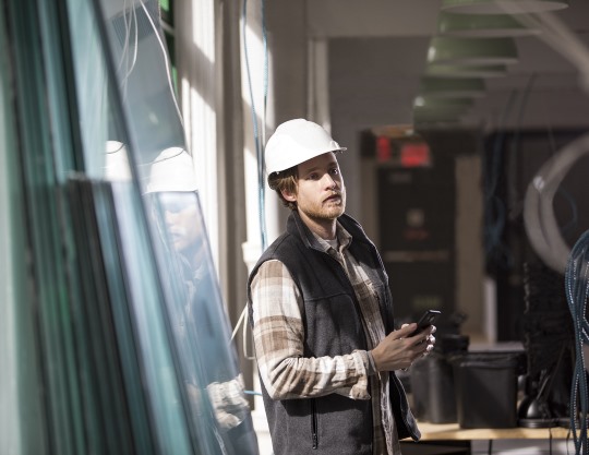 A man in a hard hat holds a Microsoft phone