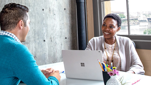 Woman with Surface book speaking to coworker