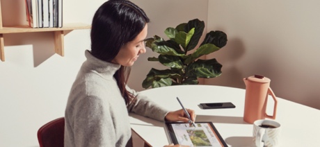 Woman sitting in a kitchen working on a tablet