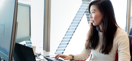 Woman sitting at a desk near a window working on a computer