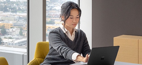 Woman sitting near a window typing on a laptop