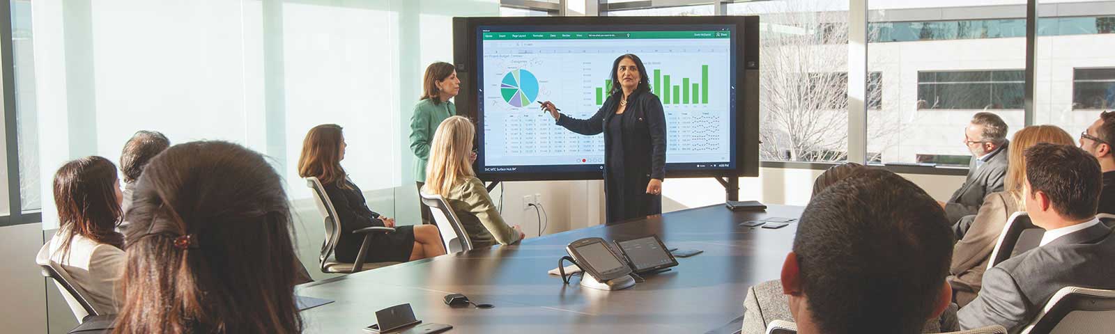 Woman presenting on smartboard in front of coworkers