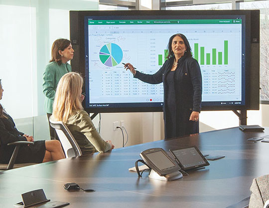 Woman presenting on smartboard in front of coworkers