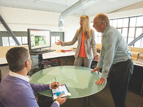 Two men and one woman meeting and working with tablets