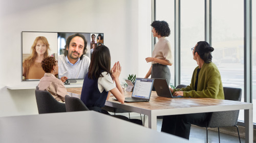 Female speaker presenting in a conference room with remote attendees
