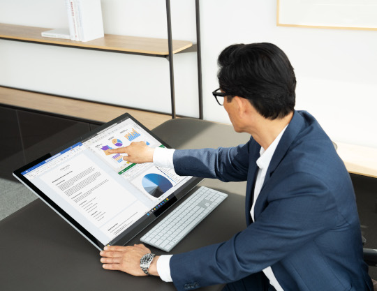 Man sitting at his office desk working on a Surface Studio 2
