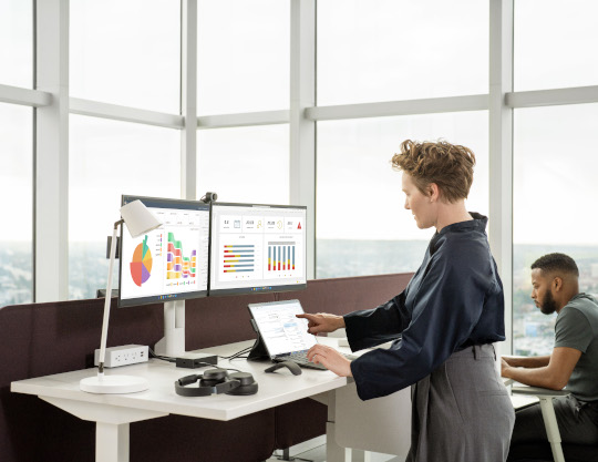 Woman standing at a desk in the office working on a Surface Pro 9