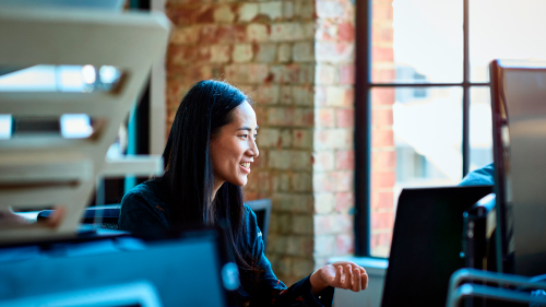 Office worker, smiling and looking away, sitting in front of a computer