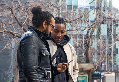 Two developers walking outside looking at a phone together