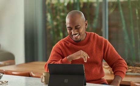 A smiling man working on his laptop at home