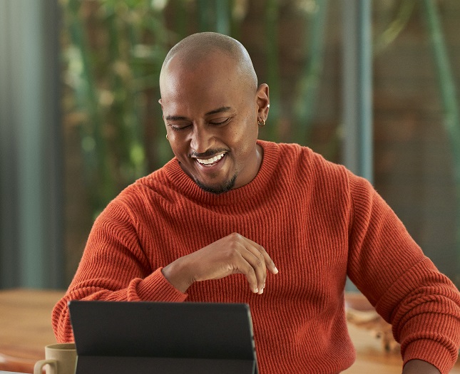A smiling man working on his laptop at home