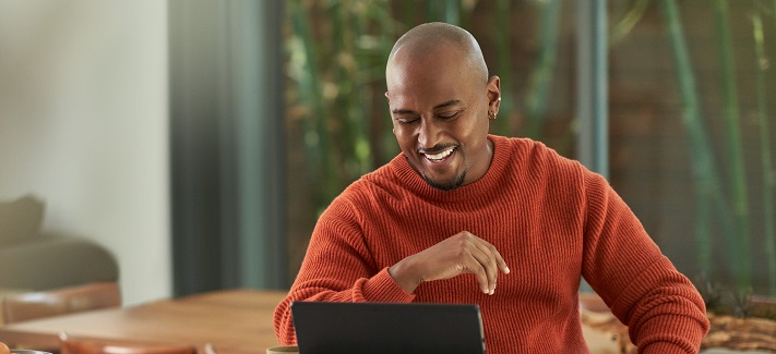 A smiling man using his tablet in his home office