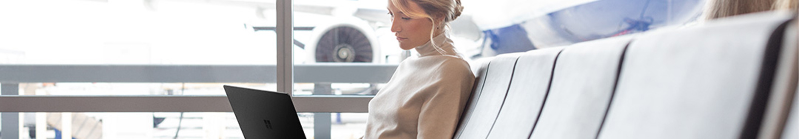 The photo shows a woman sitting with the laptop at the airport.