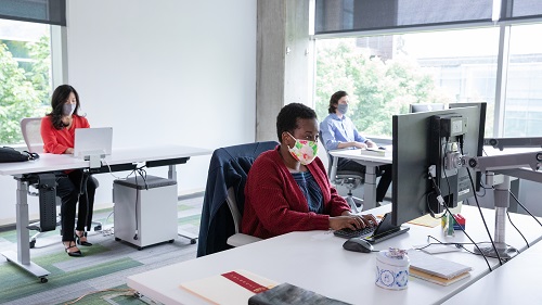 3 people wearing masks working in an office