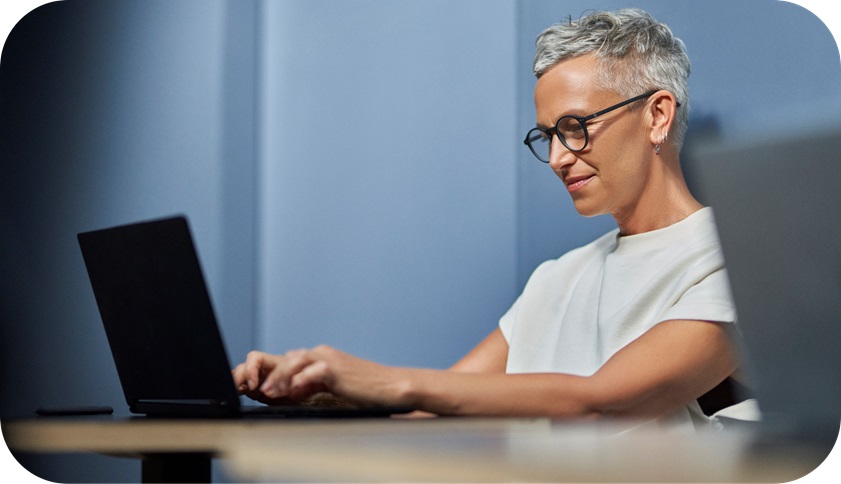 A smiling person typing on their laptop