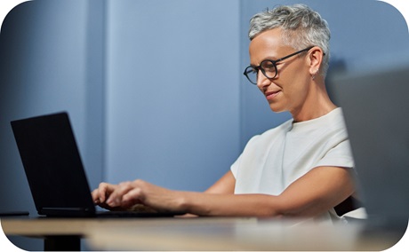 A smiling person typing on their laptop