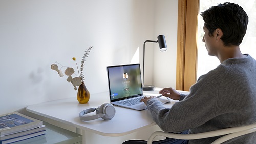 A man logging into his computer in his home office