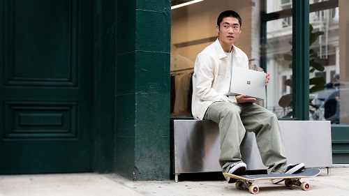 A young tech worker with a laptop and skateboard