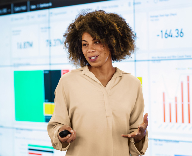 A professional presents in front of a video screen