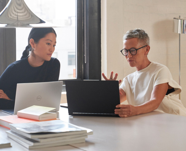 A woman showing her laptop’s screen to the woman next to her