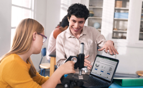 A woman addressing another woman’s attention to laptop’s screen