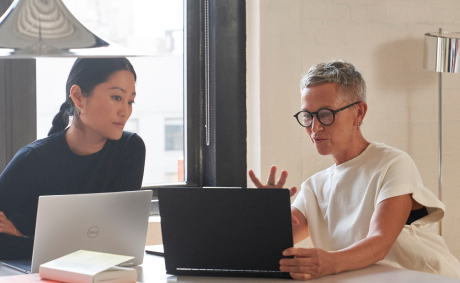 A woman showing her laptop’s screen to the woman next to her