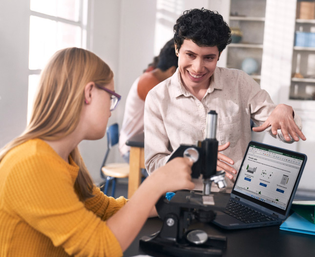 A woman addressing another woman’s attention to laptop’s screen