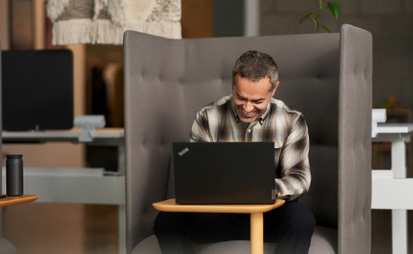 A laughing man in front of his laptop in a private booth