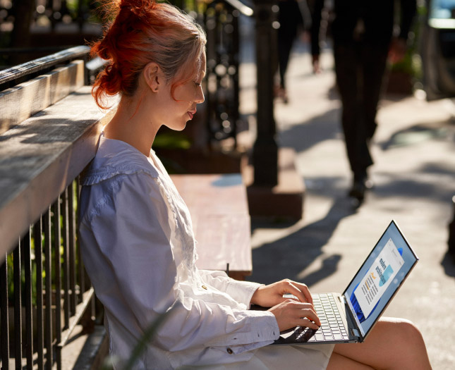 A woman working on her laptop at a park