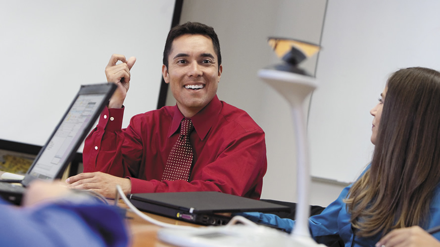A man smiles at others in a conference room